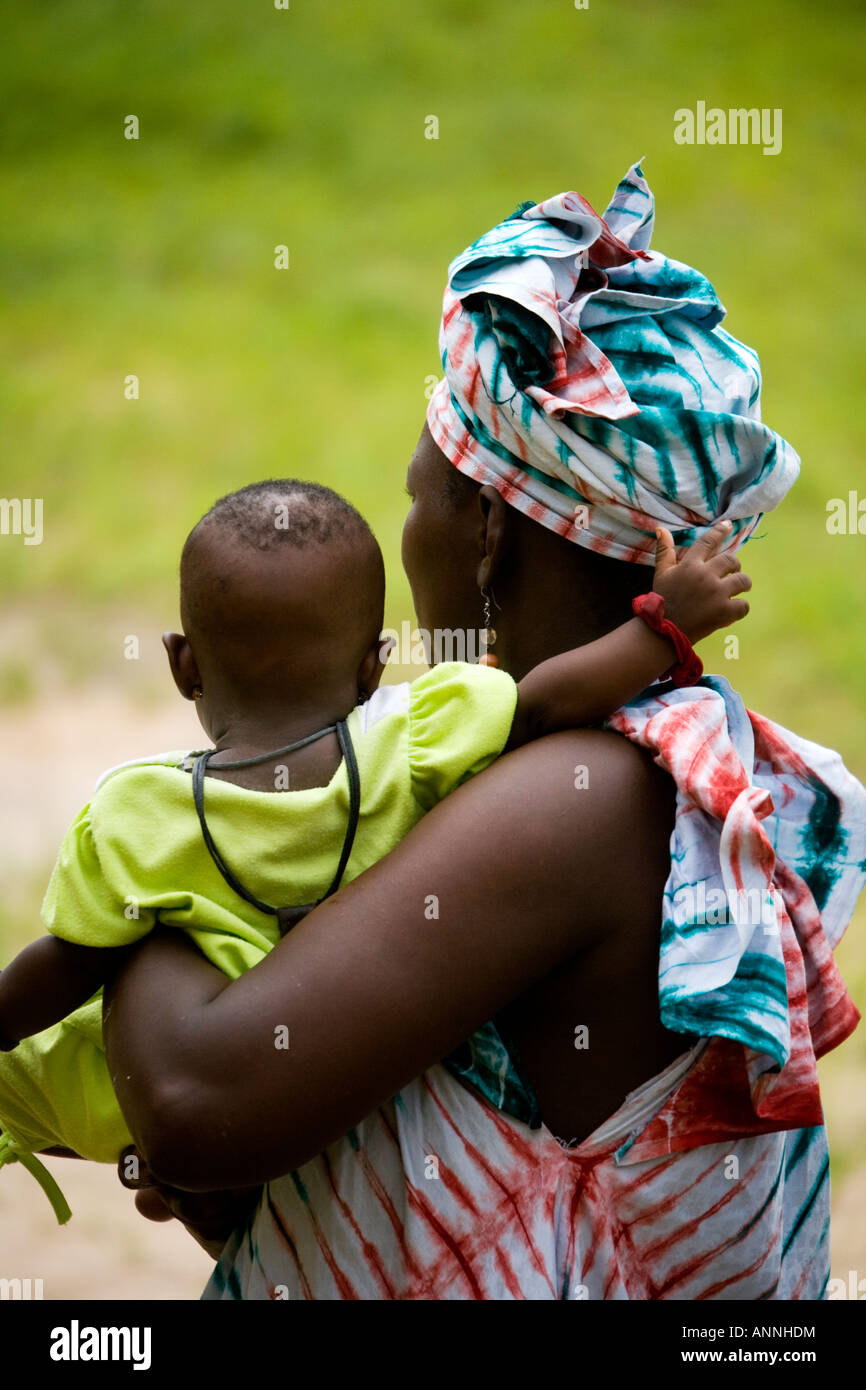 Back view of a Gambian African mother holding her baby.  She is wearing typical Gambian clothes. Stock Photo