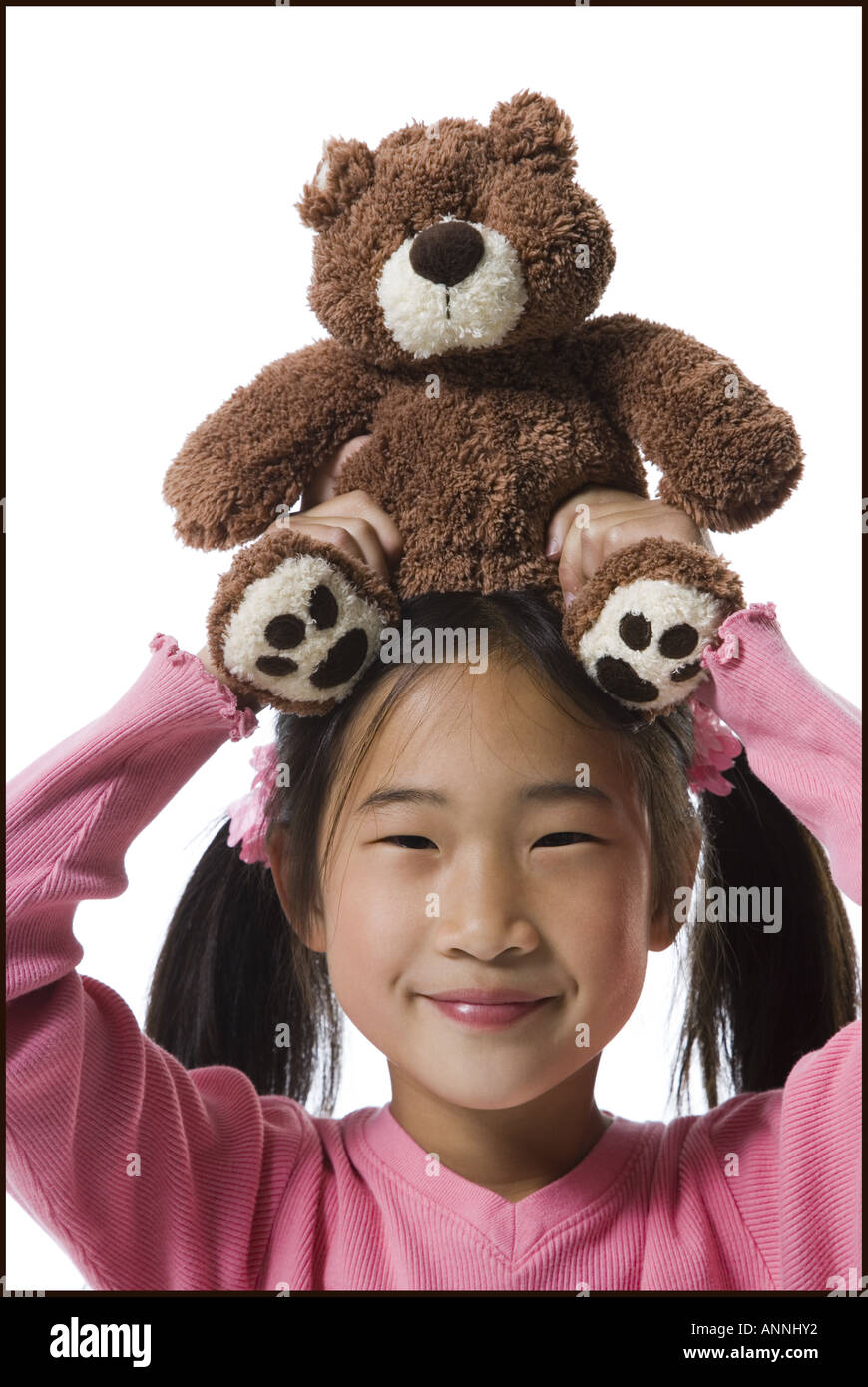 Portrait of a girl holding a teddy bear over her head and smiling Stock Photo
