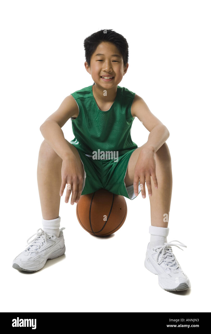 Portrait of a boy sitting on a basketball and smiling Stock Photo - Alamy