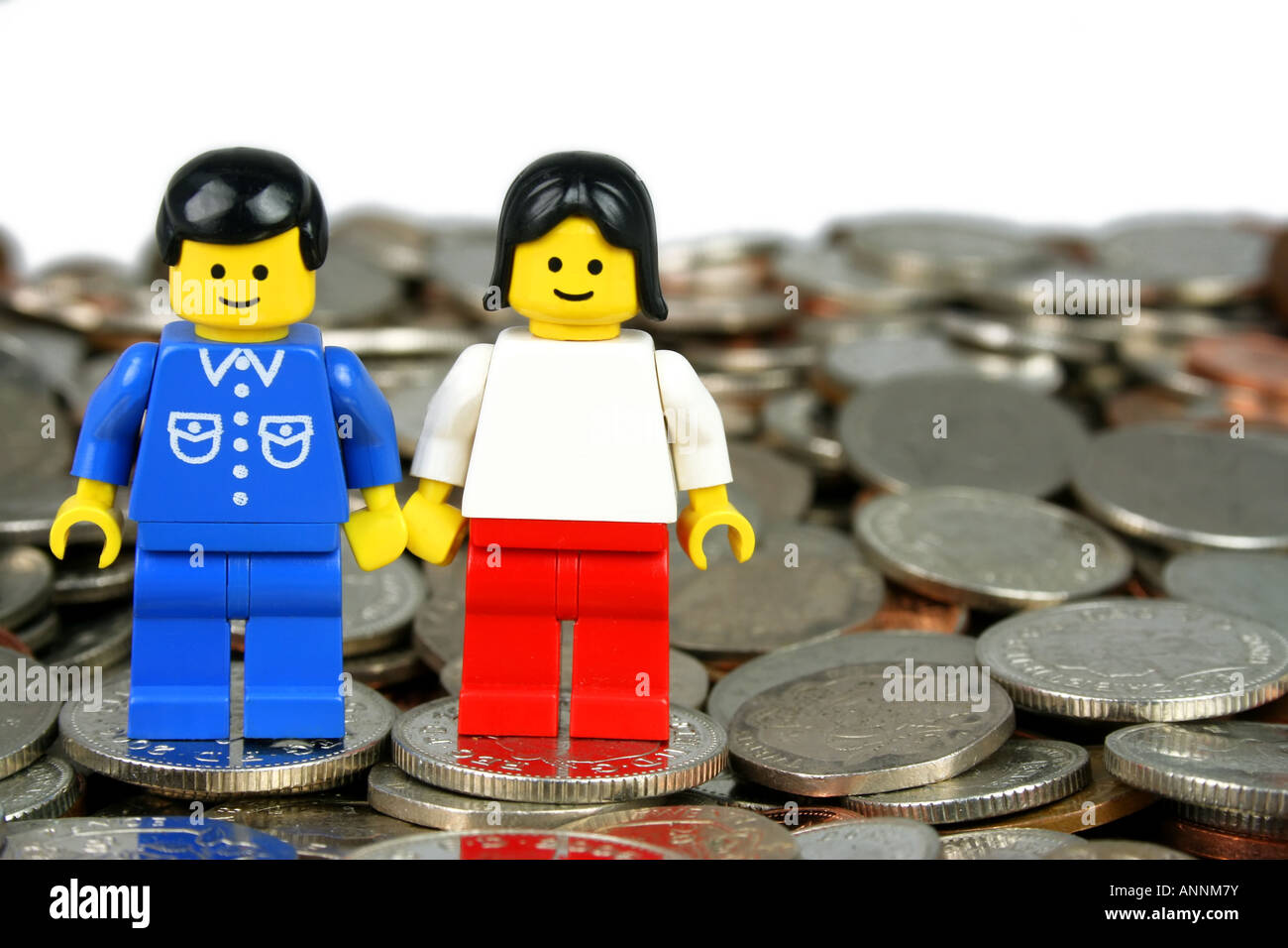 Lego man and woman standing on coins - 'in the money' concept Stock Photo