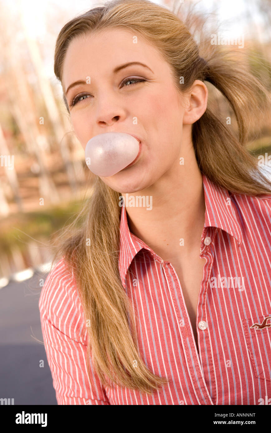 Stock photo showing closeup of caucasian teen girl from 15 to 17 years smiling and blowing bubble with gum USA Stock Photo