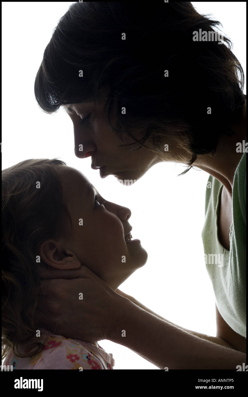 Close up of a mid adult woman kissing her daughter s forehead Stock Photo