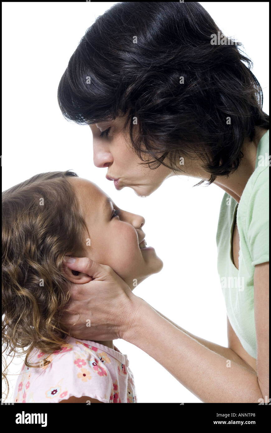 Close up of a mid adult woman kissing her daughter s forehead Stock Photo