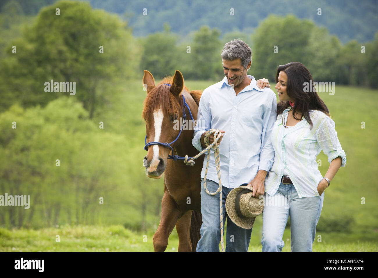 man and a woman walking with a horse Stock Photo