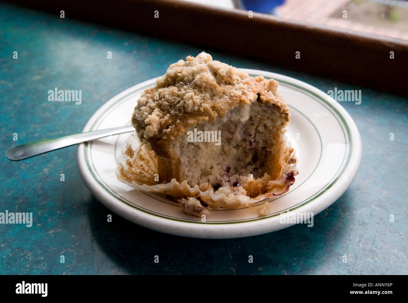 Fork and partially eaten crumb cake muffin on a plate and a cup of coffee in a cafe Stock Photo