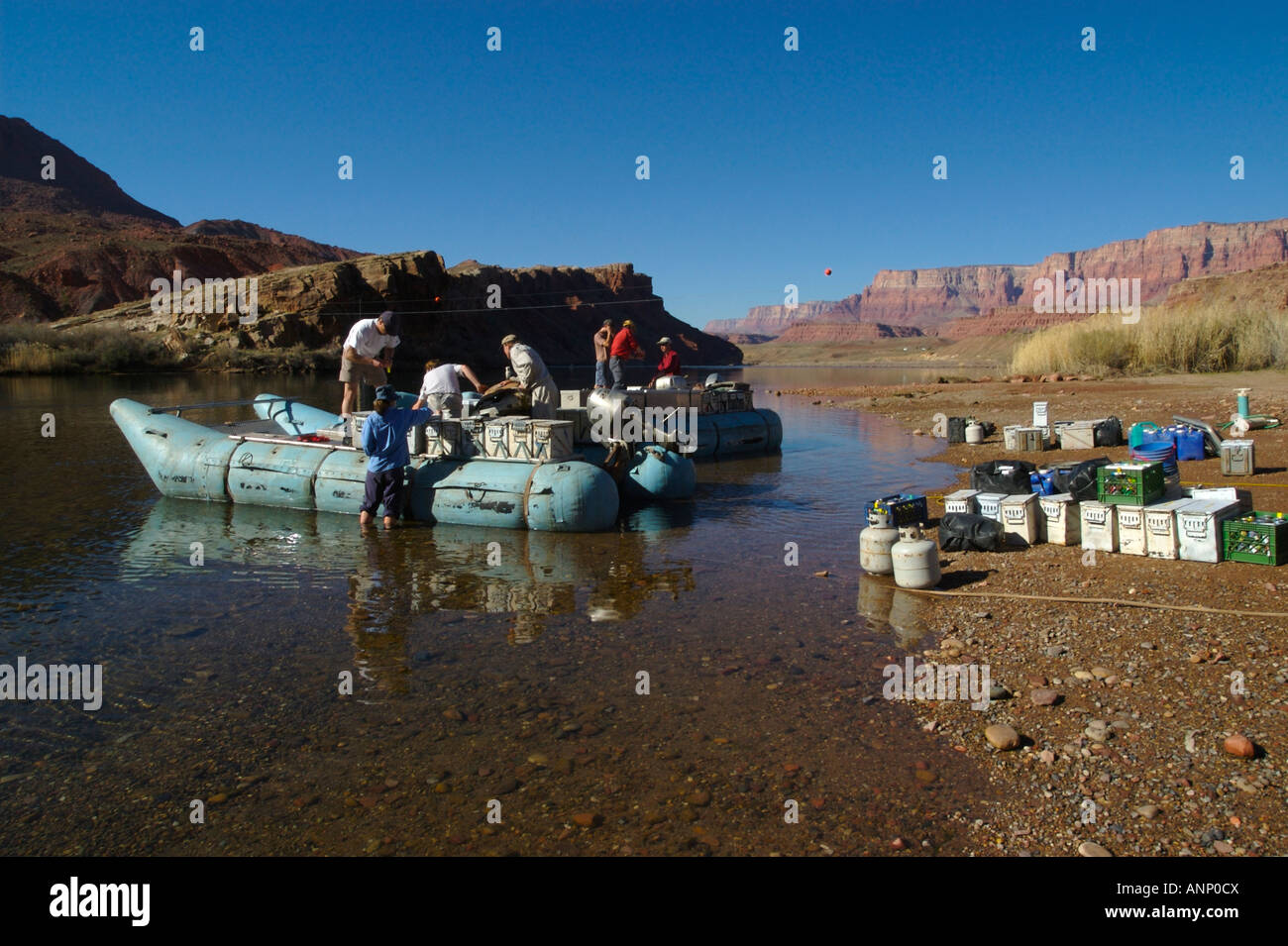 People loading coolers and gear on rafts at Lees Ferry for a whitewater river rafting trip down the Colorado River, Grand Canyon Stock Photo