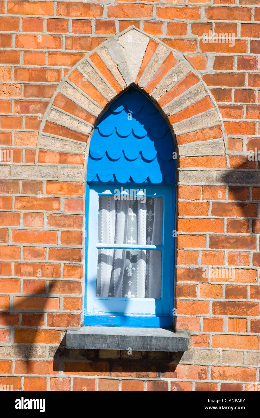 An attractive period window with blue painted frame and pointed brickwork arch Stock Photo
