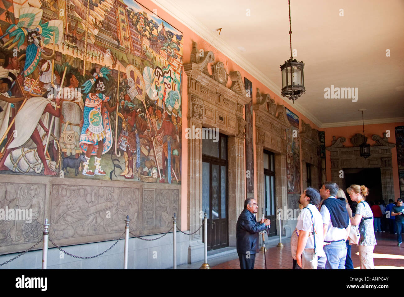 Tour guide showing tourists murals painted by Diego Rivera at the National Palace in Mexico City Mexico Stock Photo