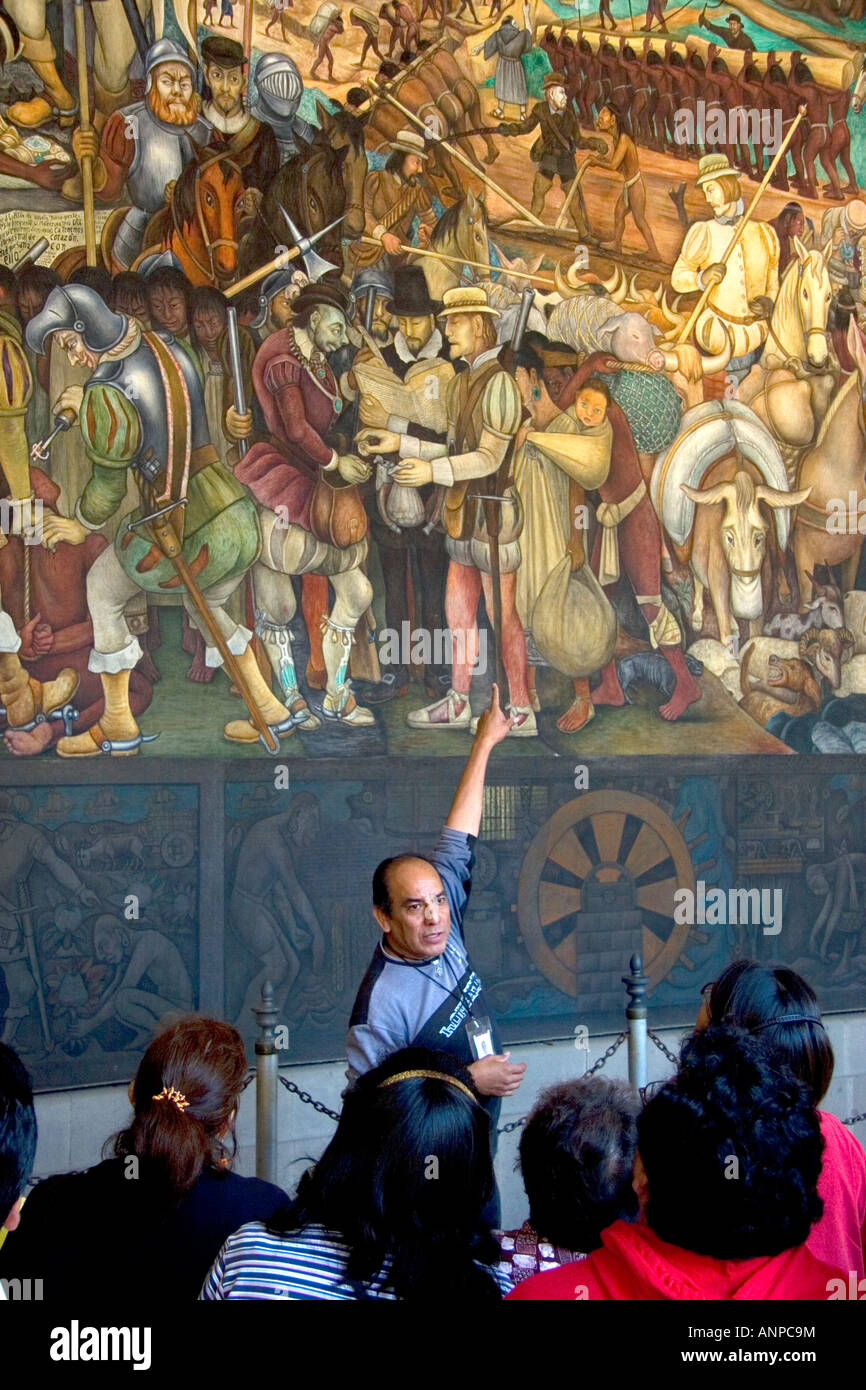 A tour guide showing tourists a mural painted by Diego Rivera at the National Palace in Mexico City Mexico Stock Photo