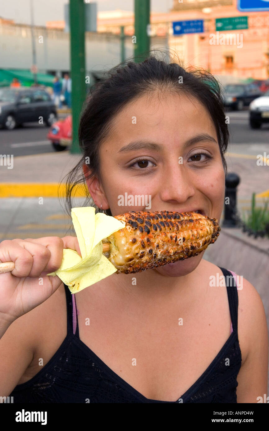 Mexican girl eating an ear of roasted corn on the cob in Mexico City