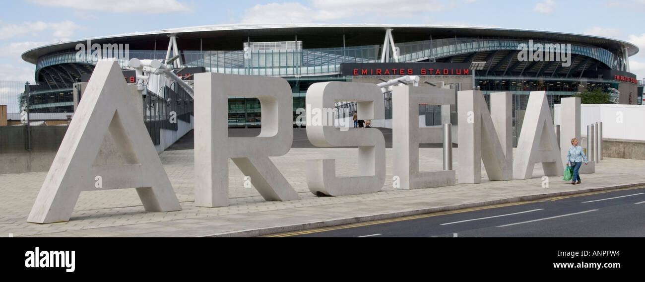 Arsenal FC football club Emirates stadium modern building & stone sign in big lettering pedestrian walking past adds scale Holloway London England UK Stock Photo