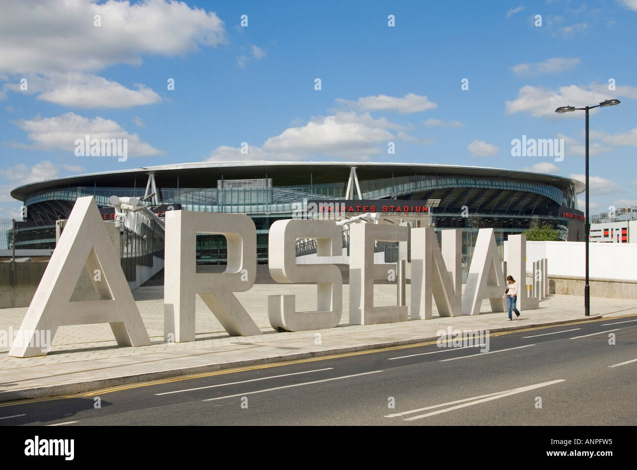 Arsenal football FC club Emirates stadium modern building & stone sign in big lettering pedestrian walking past adds scale Holloway London England UK Stock Photo