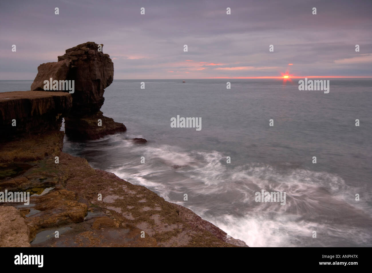 Dusky sunset over rough seas at Pulpit Rock Isle of Portland Dorset UK Stock Photo