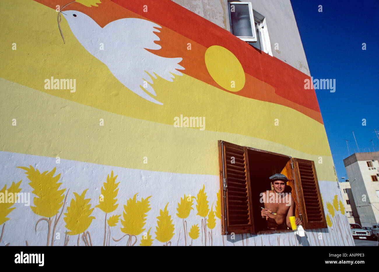 Bird of peace mural and resident artist with his artwork at his open window Las Palmas town Vegueta Gran Canaria Canary Islands Spain Stock Photo