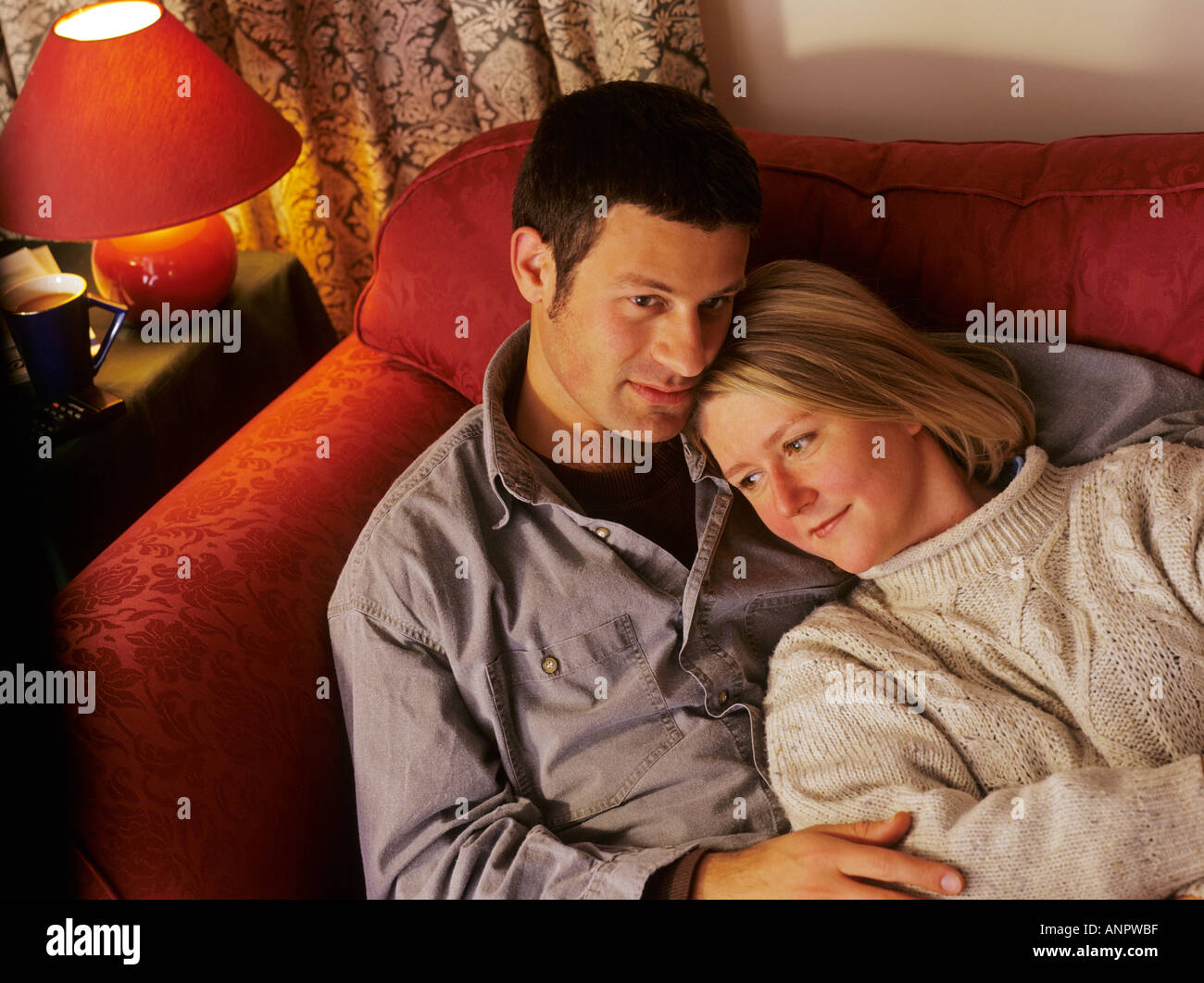 Affectionate young couple together on sofa at home Stock Photo