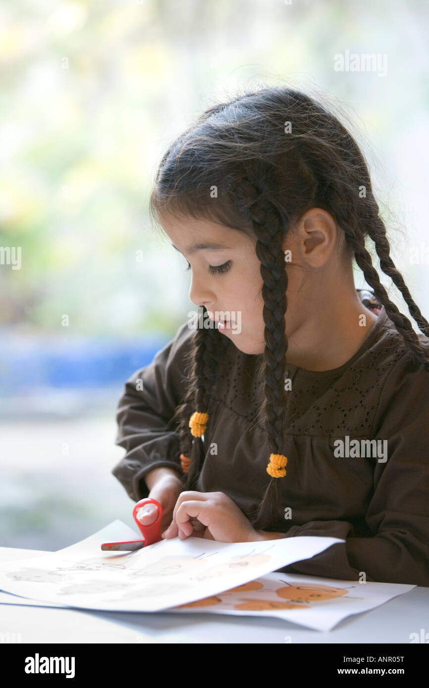 Little girl cutting paper with scissors Stock Photo