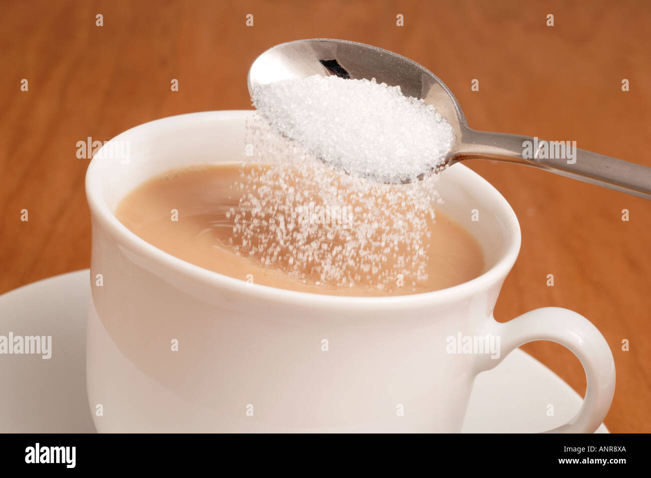 Adding white granulated sugar to cup of tea Stock Photo Alamy