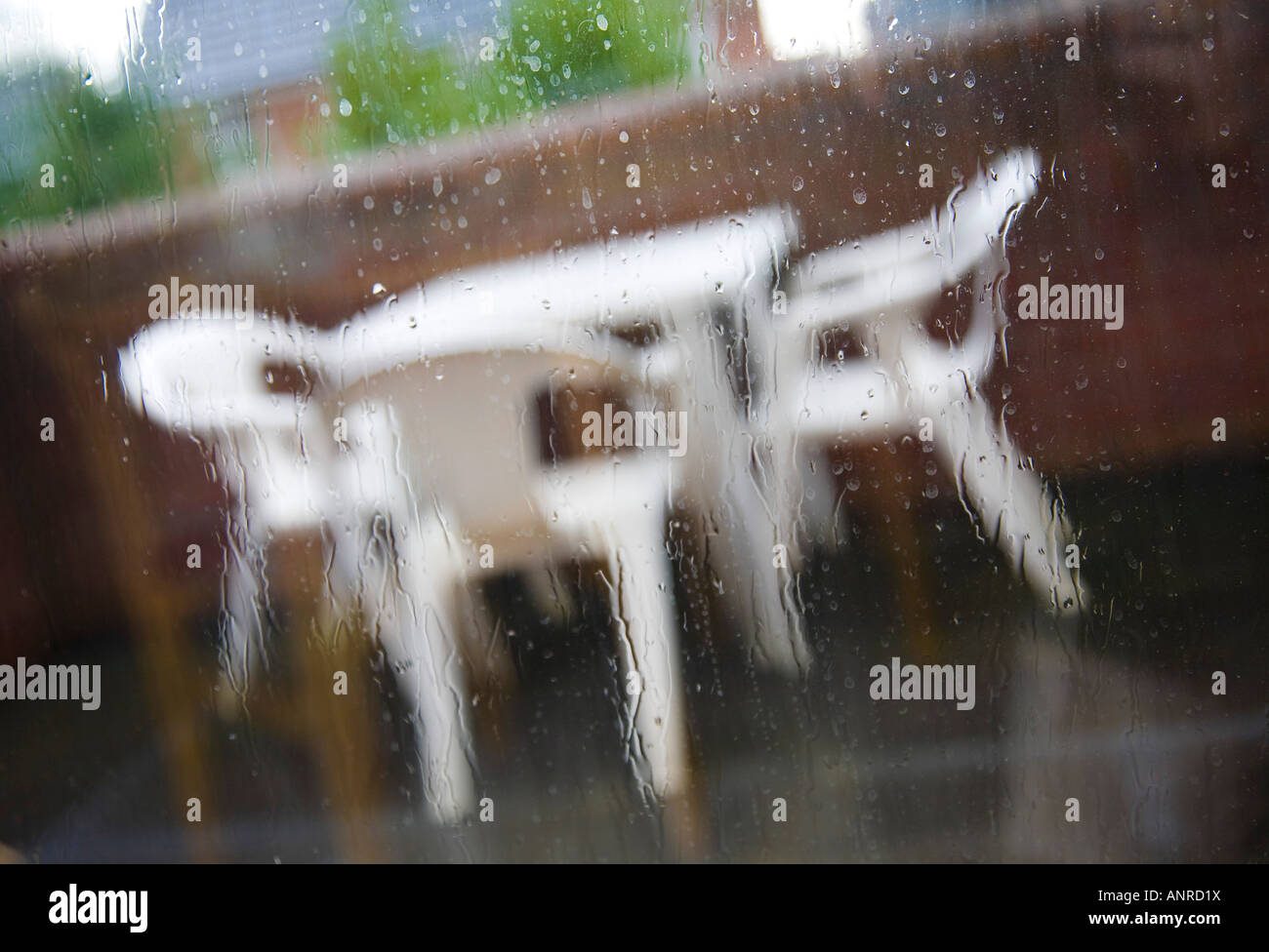 Patio furniture in the rain. Seen through a rain spattered window Stock Photo Alamy