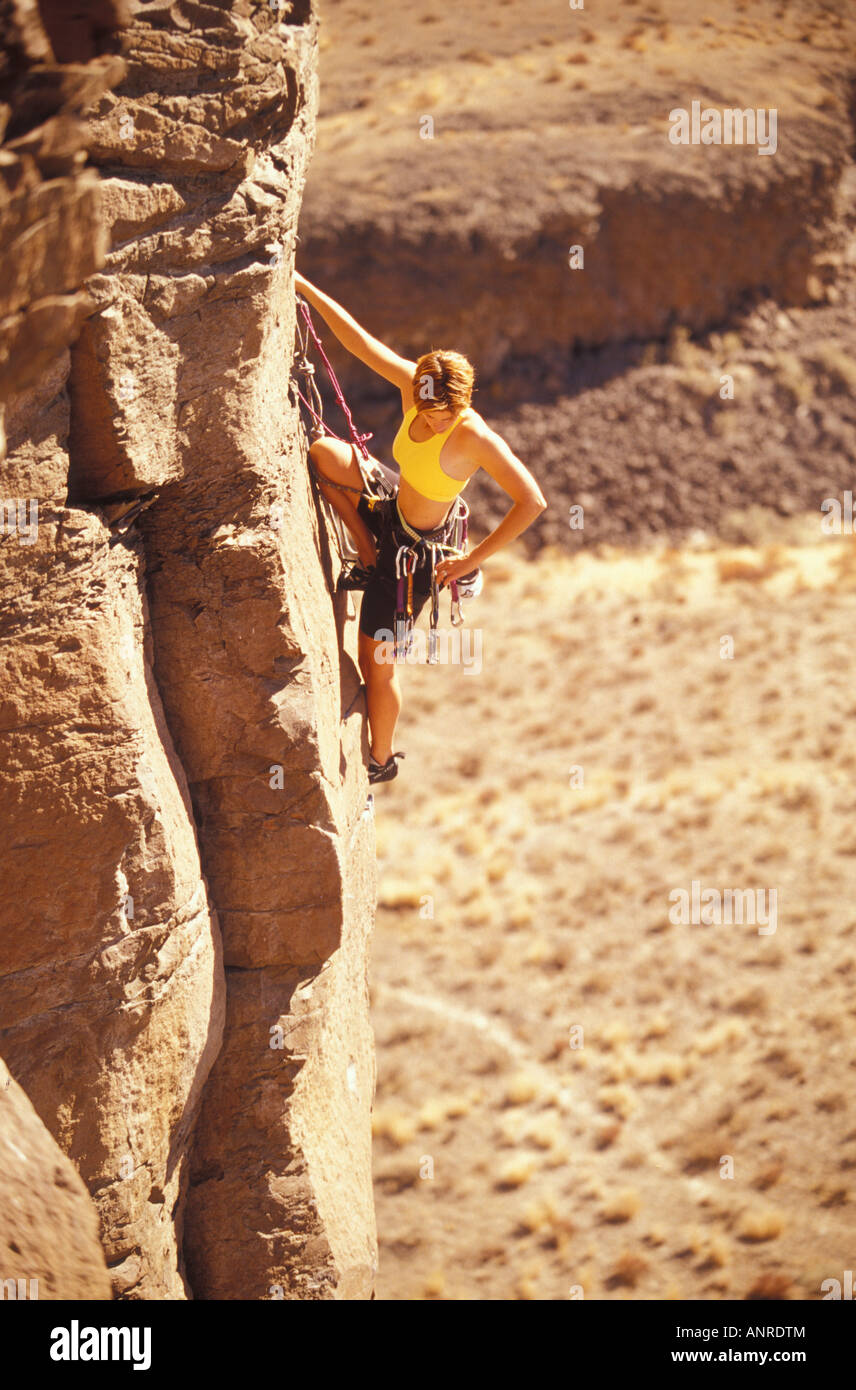 A woman rock climber selects a chock from her array of climbing gear