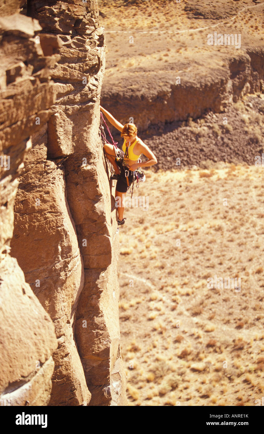 A young woman rock climber selects a climbing aid from the rack on her