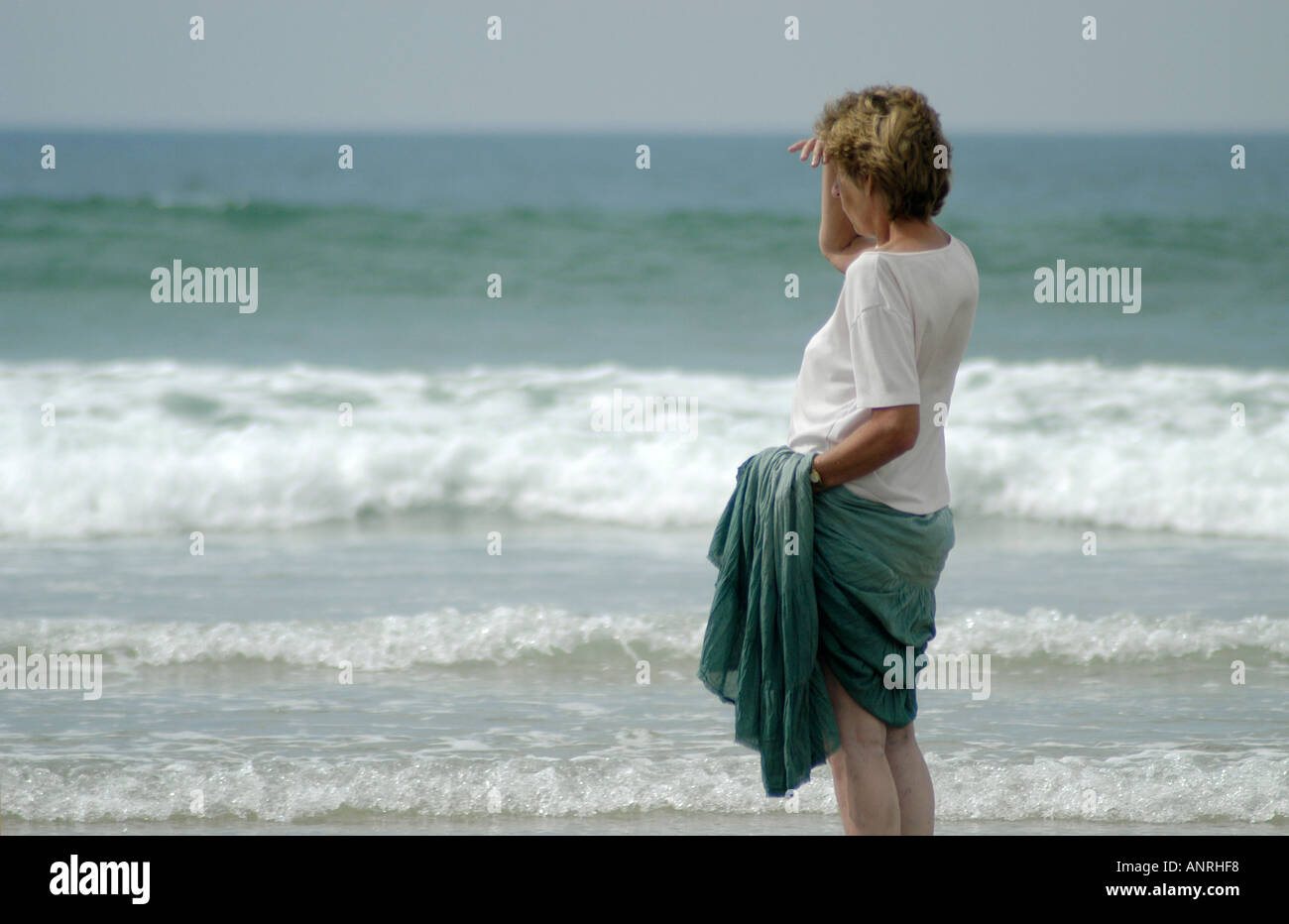 Woman stood on the beach and looking out to sea Stock Photo - Alamy