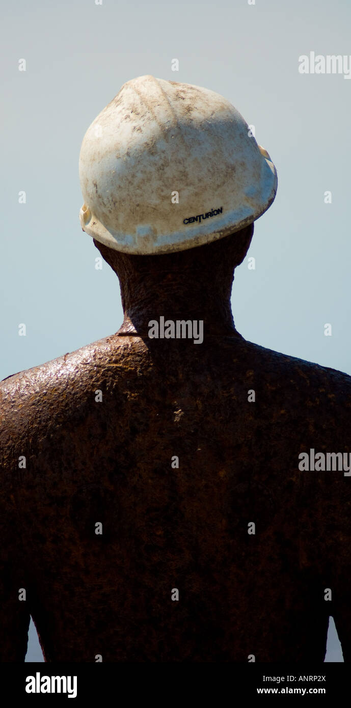 Cast iron man wearing a construction hat, part of Antony Gormley's