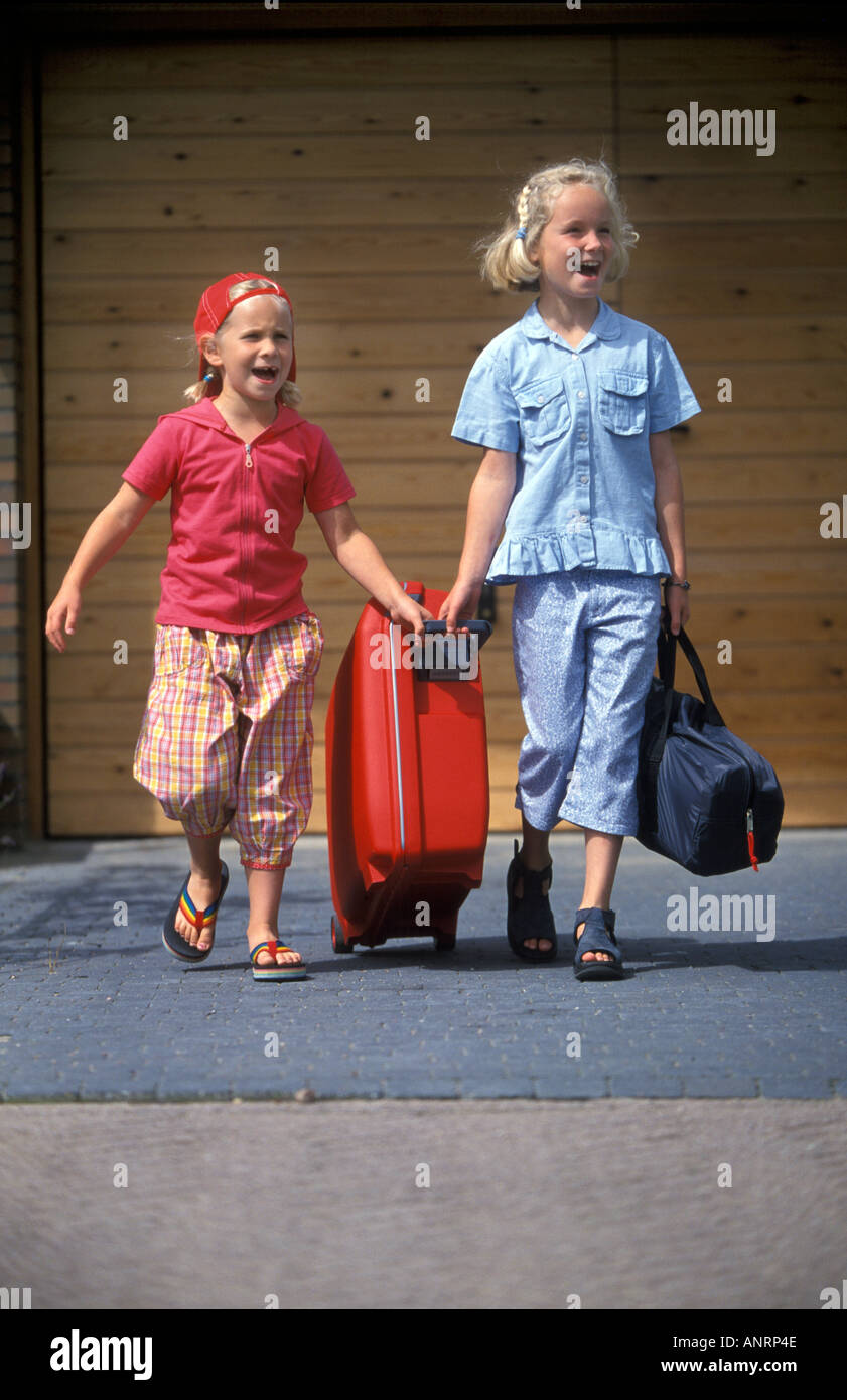 Two girls pulling a suitcase to go on vacation Stock Photo Alamy