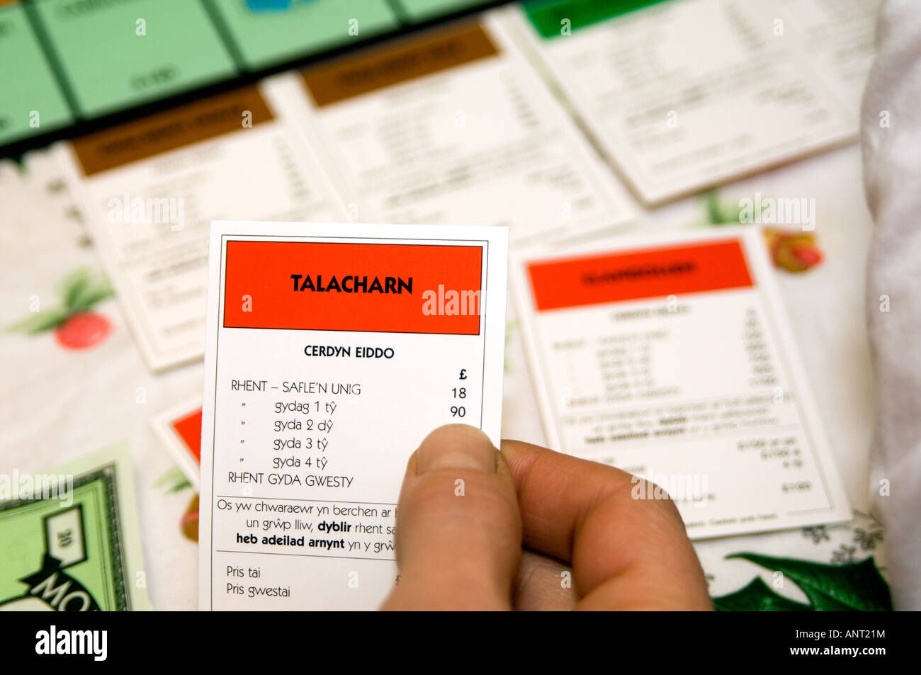 person playing welsh language Monopoly board game cymraeg wales - close up of hand holding TALACHARN property card (cerdyn eiddo Stock Photo