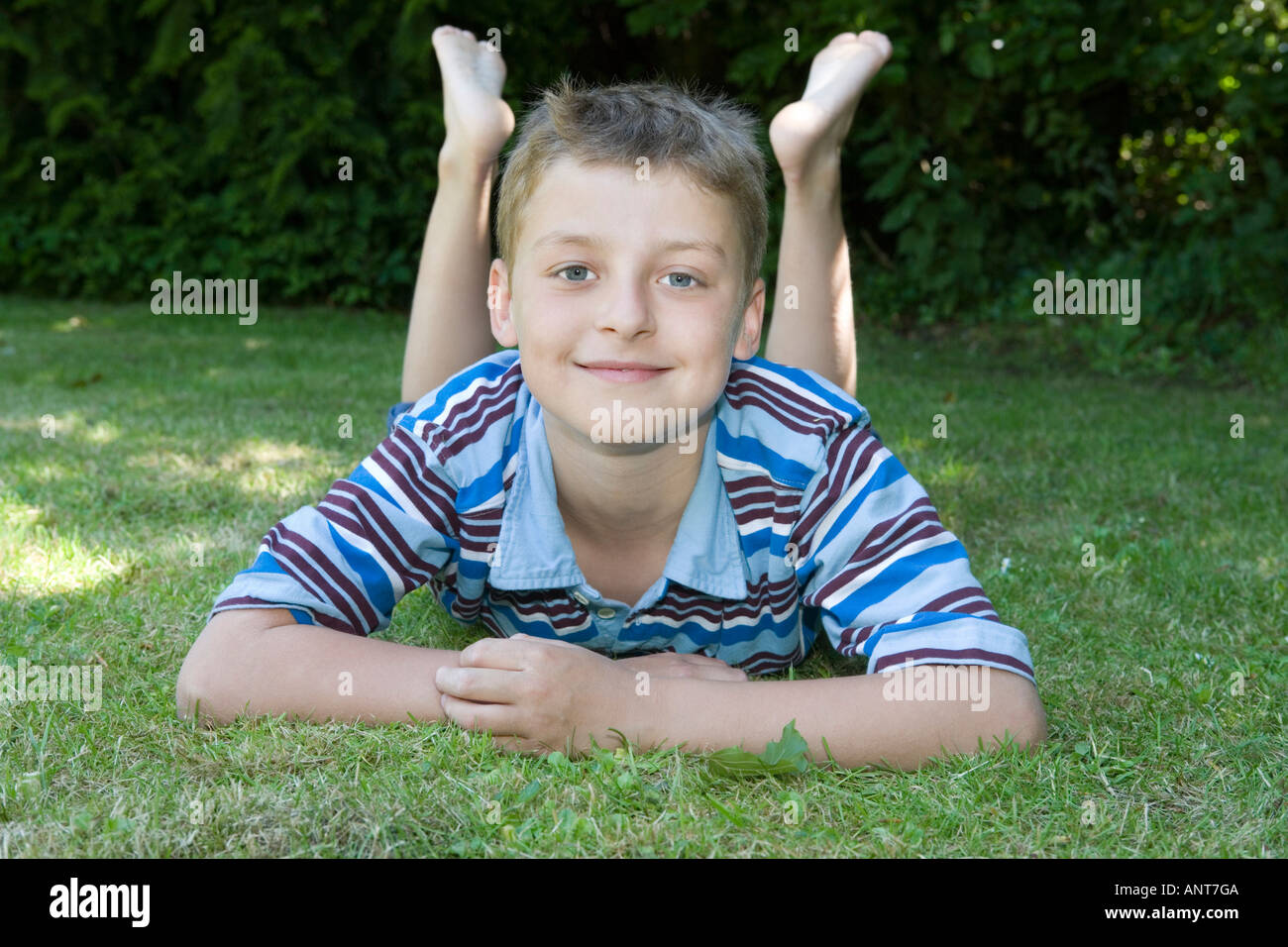 Portrait of boy lying on grass with legs raised Stock Photo