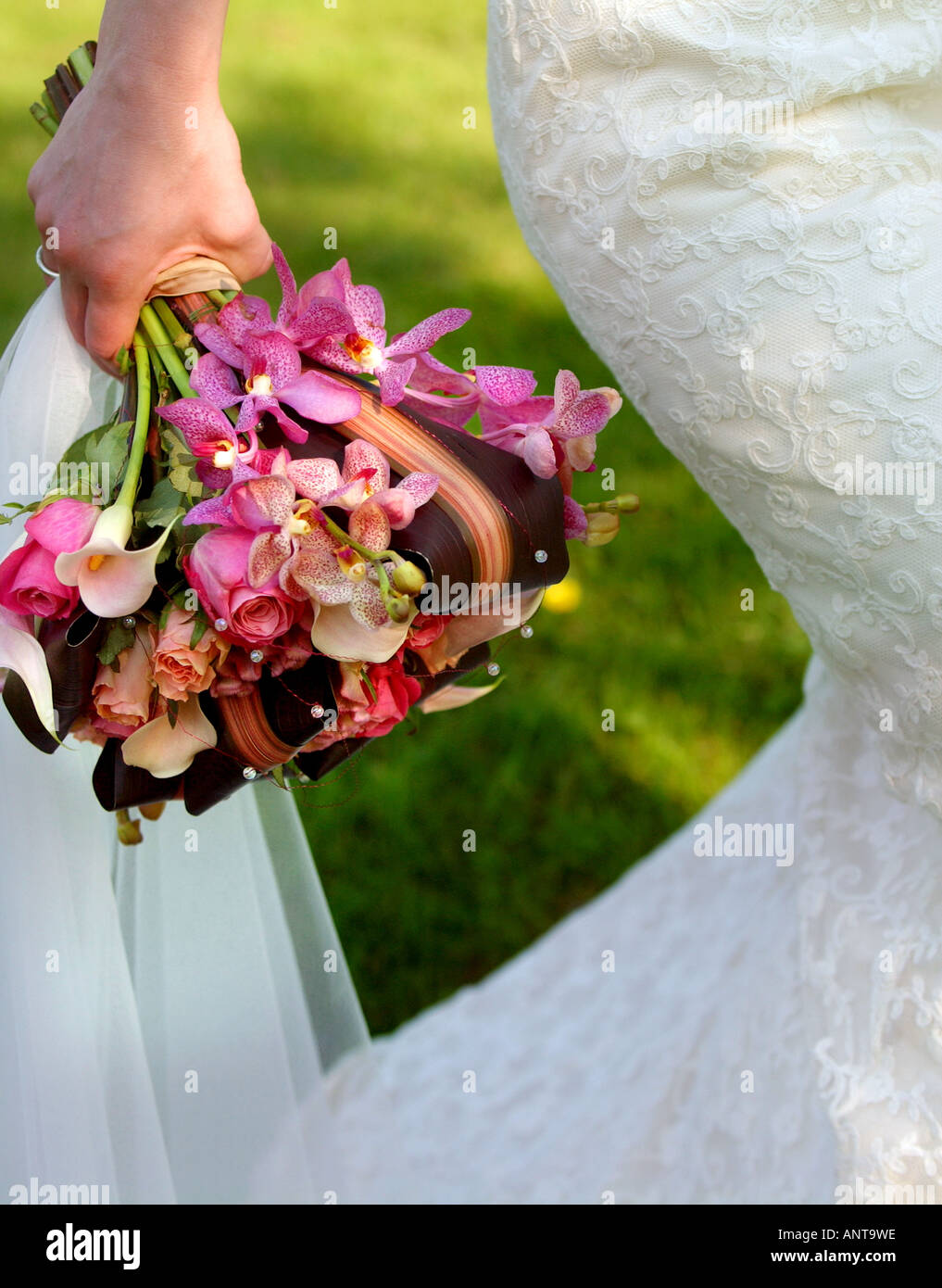 A bride carries flowers wearing a wedding dress designed and made by