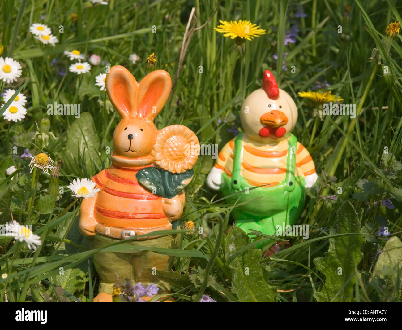 figures for Easter decoration Easter bunny and funny hen in grass on flowering meadow Stock Photo