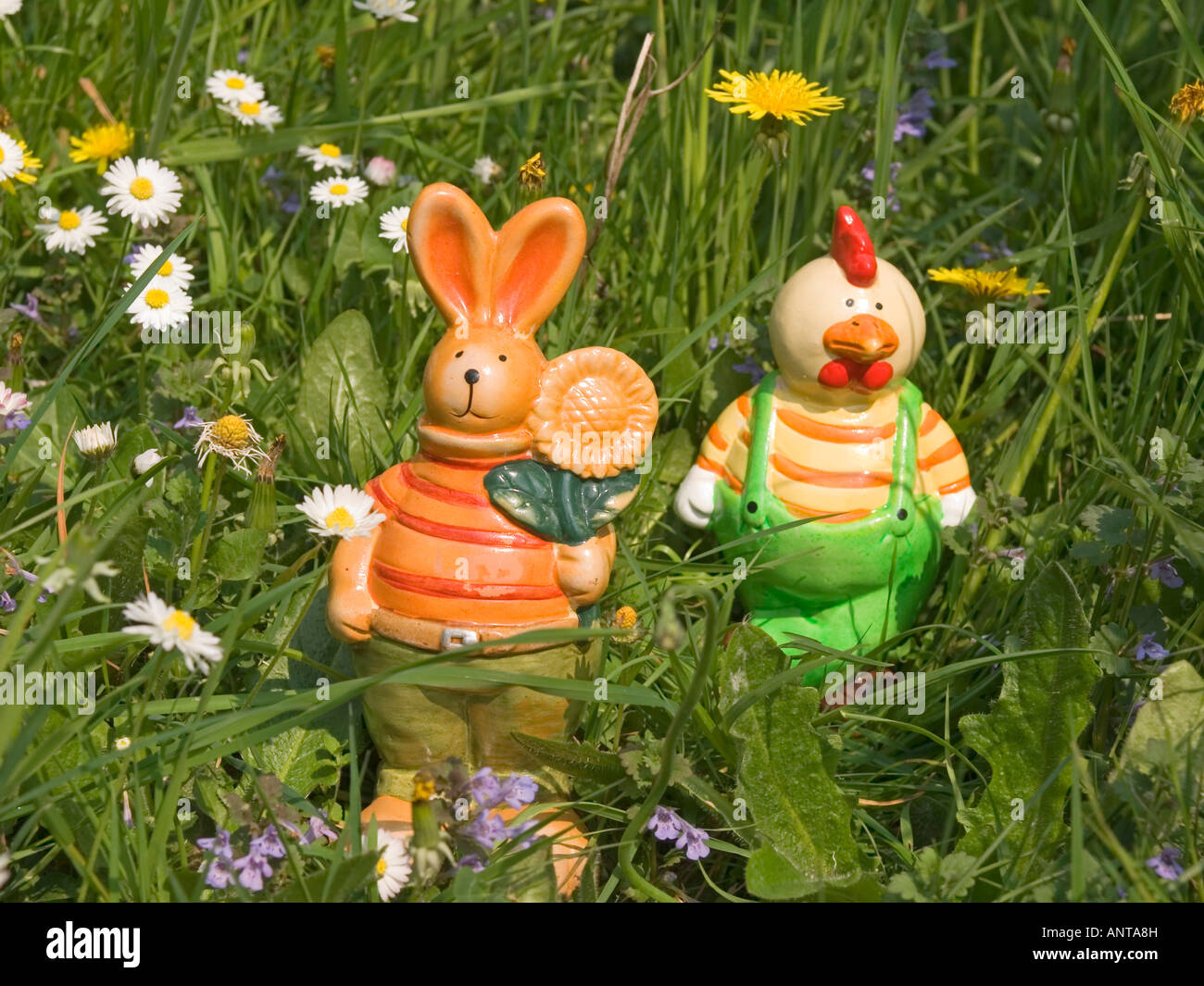 figures for Easter decoration Easter bunny and funny hen in grass on flowering meadow Stock Photo