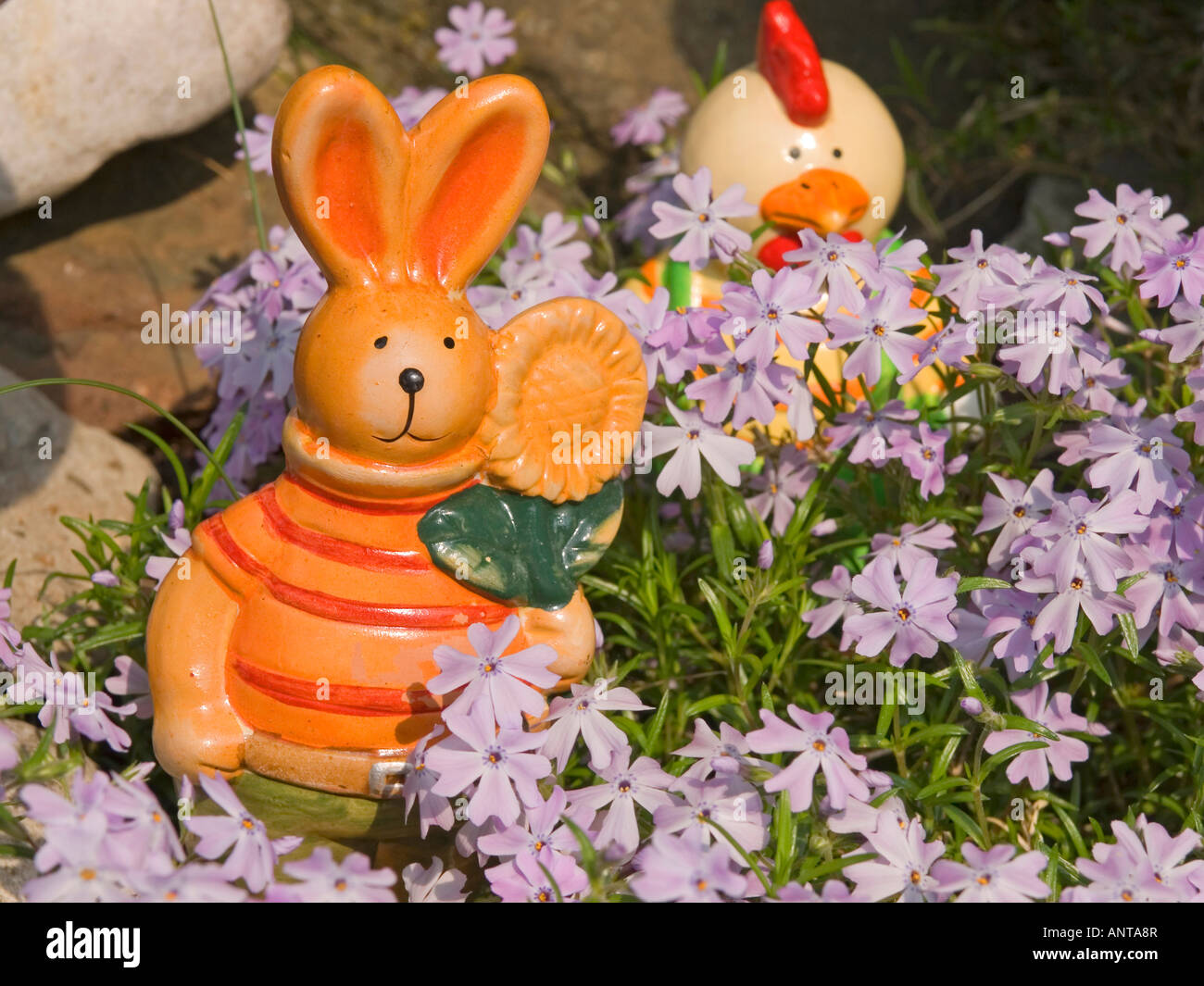 figures for Easter decoration Easter bunny and funny hen in the middle of flowers Stock Photo