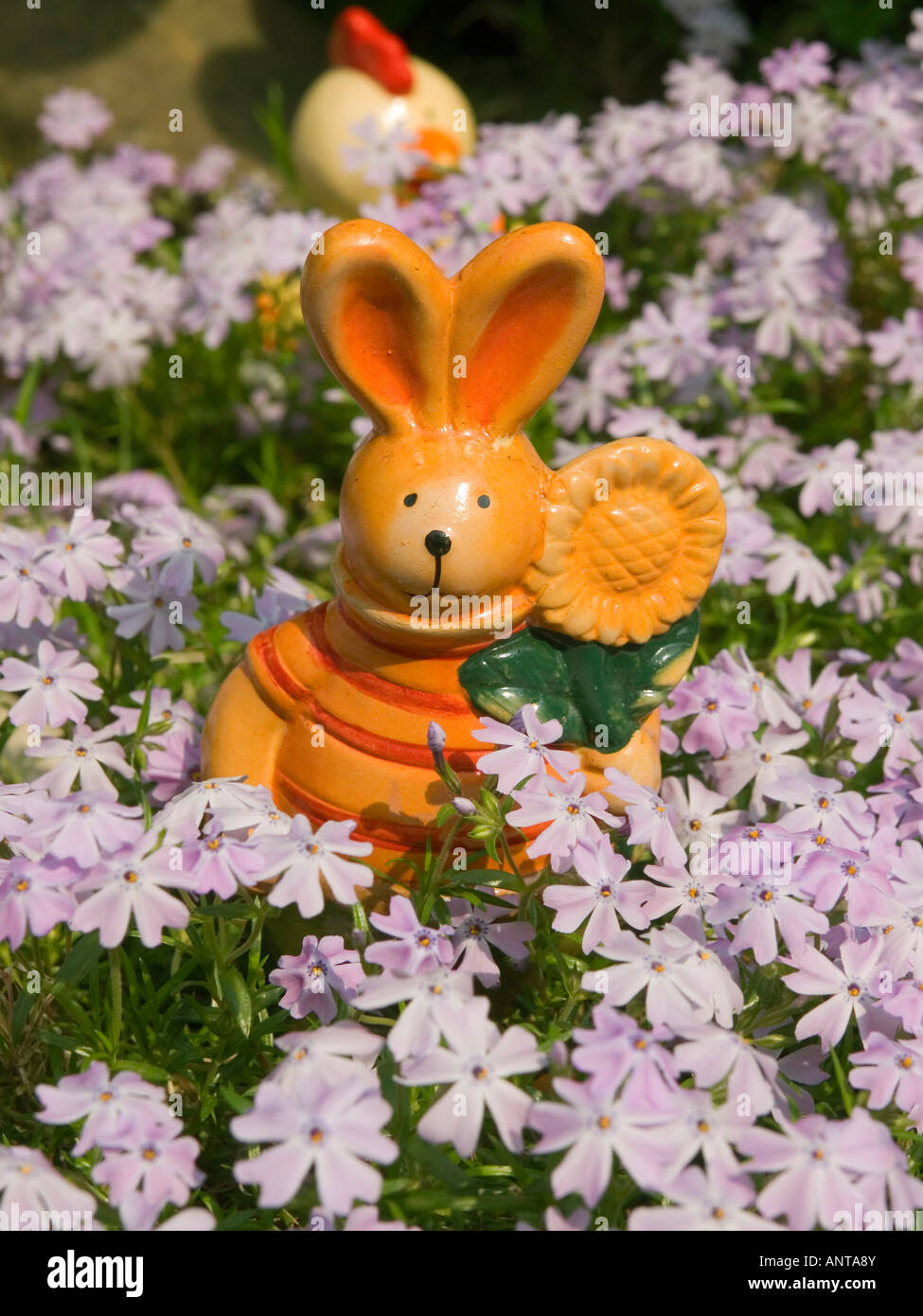 figures for Easter decoration Easter bunny and funny hen in the middle of flowers Stock Photo