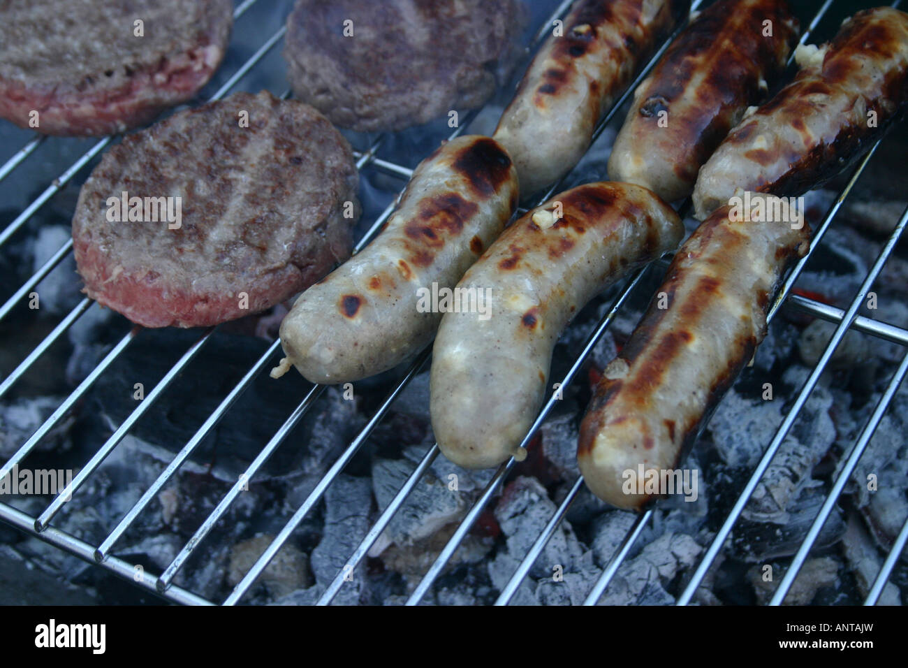 Sausages and beef burgers cooking on a barbecue Stock Photo Alamy
