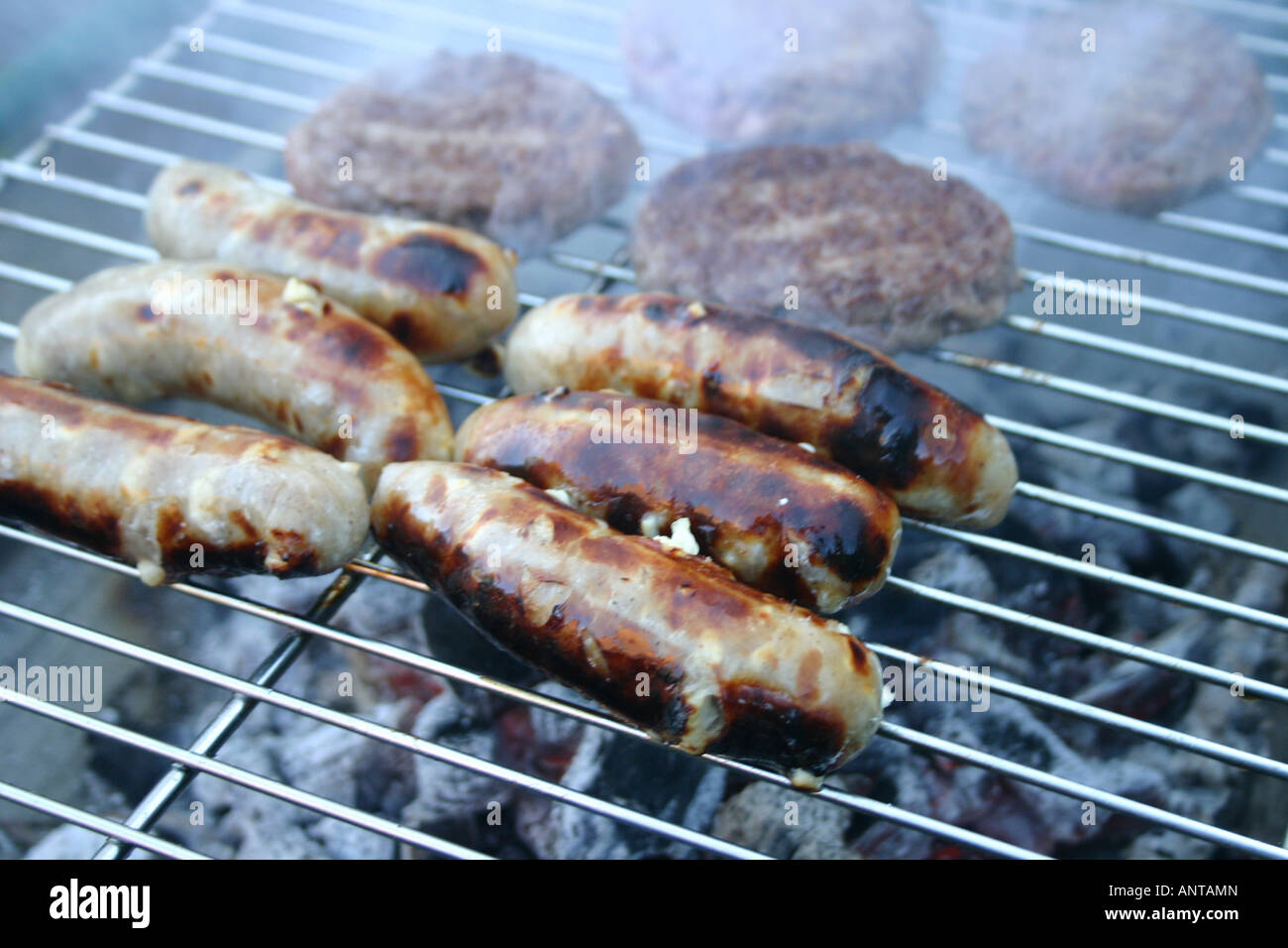 Sausages and beef burgers cooking on a barbecue Stock Photo Alamy