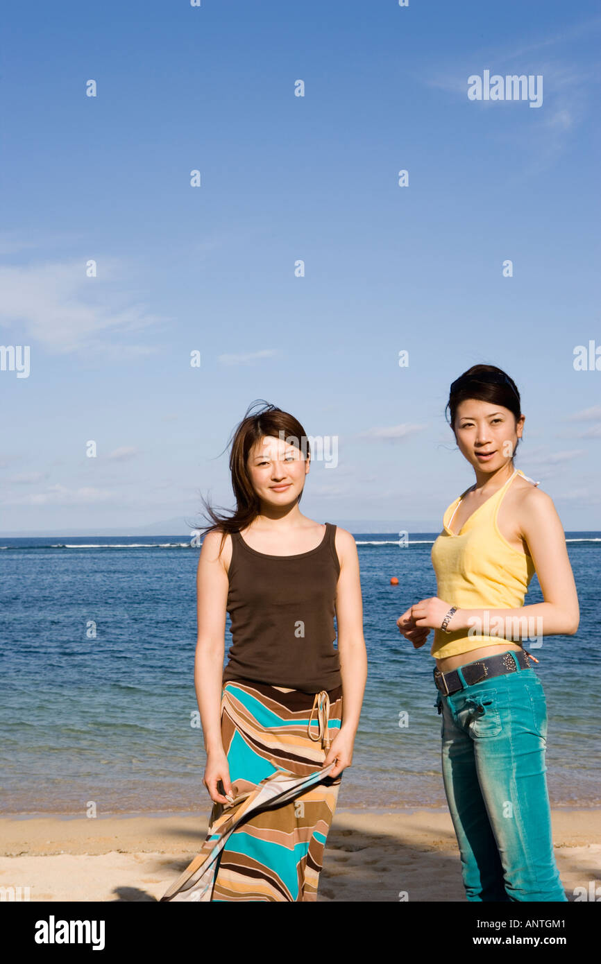 Two young women standing on beach Stock Photo - Alamy