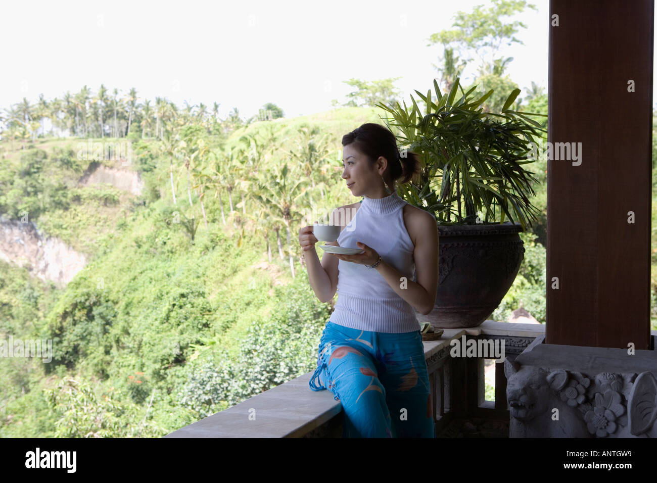 Young woman having cup of coffee on balcony Stock Photo