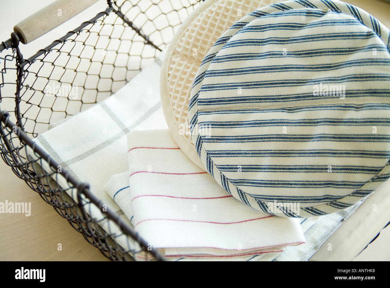 Oven mitts and towels in basket Stock Photo
