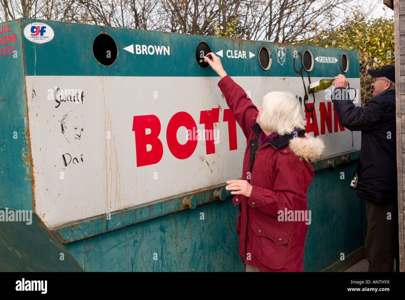 middle aged couple man and woman recycling glass bottles in a bottle bank, Aberystwyth Wales UK Stock Photo