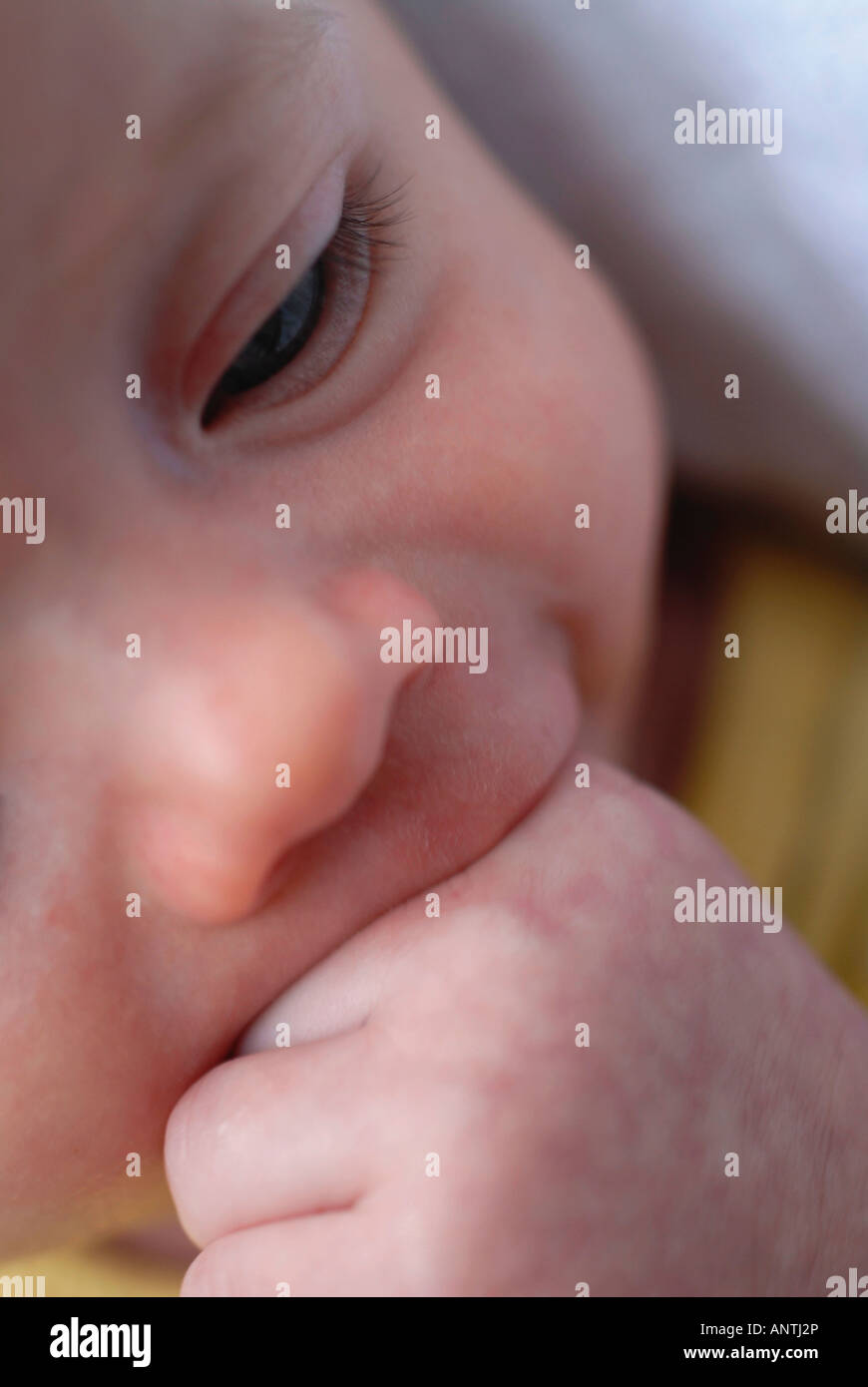 A new born baby with a hand in mouth Stock Photo