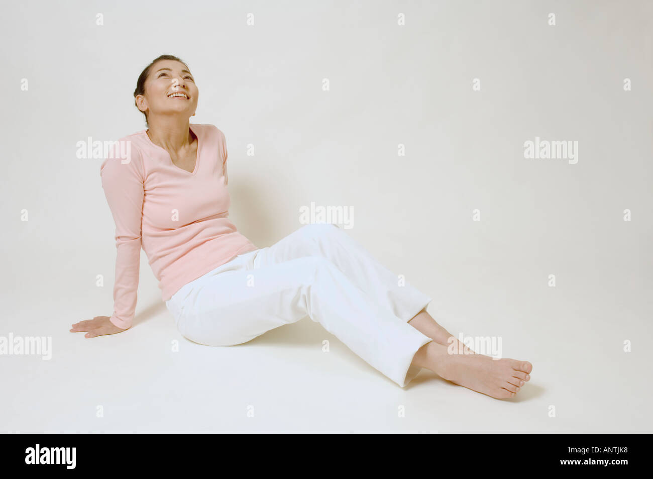 Mature woman sitting on floor smiling Stock Photo - Alamy