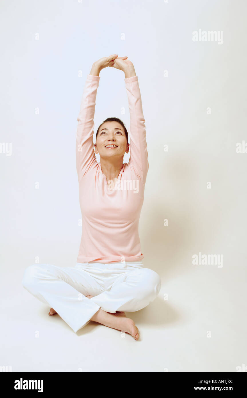 Mature woman sitting on floor stretching Stock Photo - Alamy