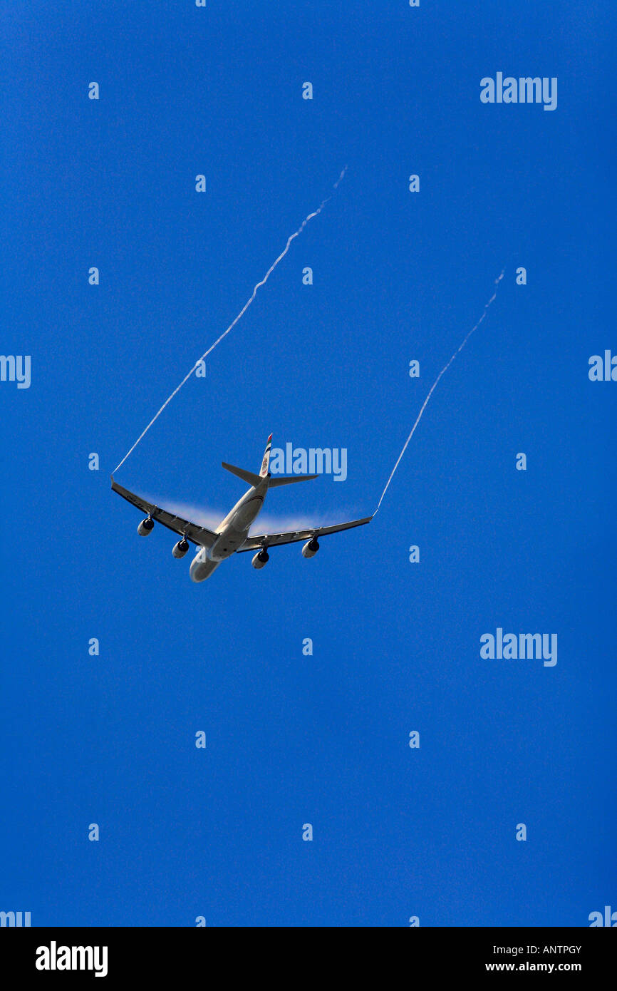 A commercial Airliner shows jetstream water vapour as it descends to land Stock Photo