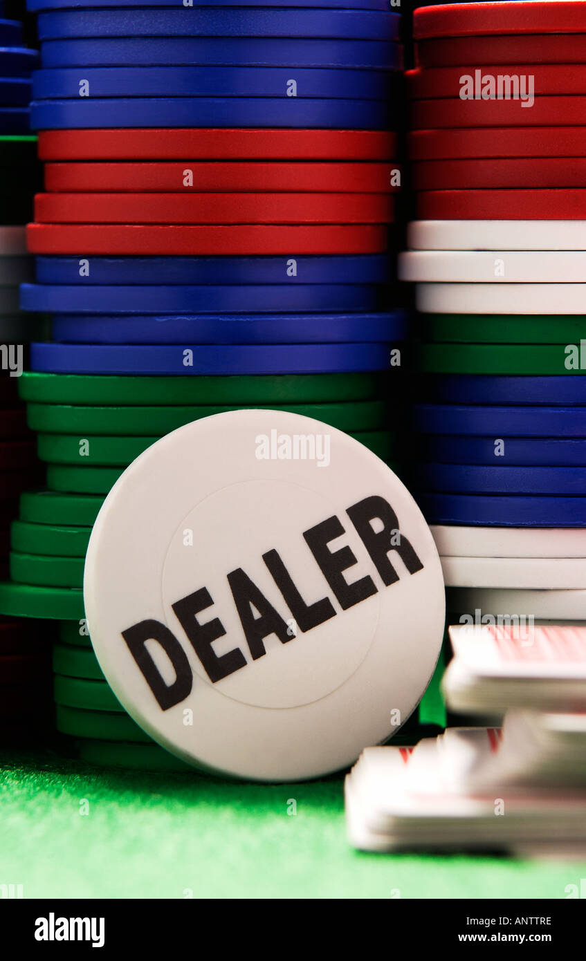 Dealers button leaning against columns of betting chips on casino table green baize Stock Photo