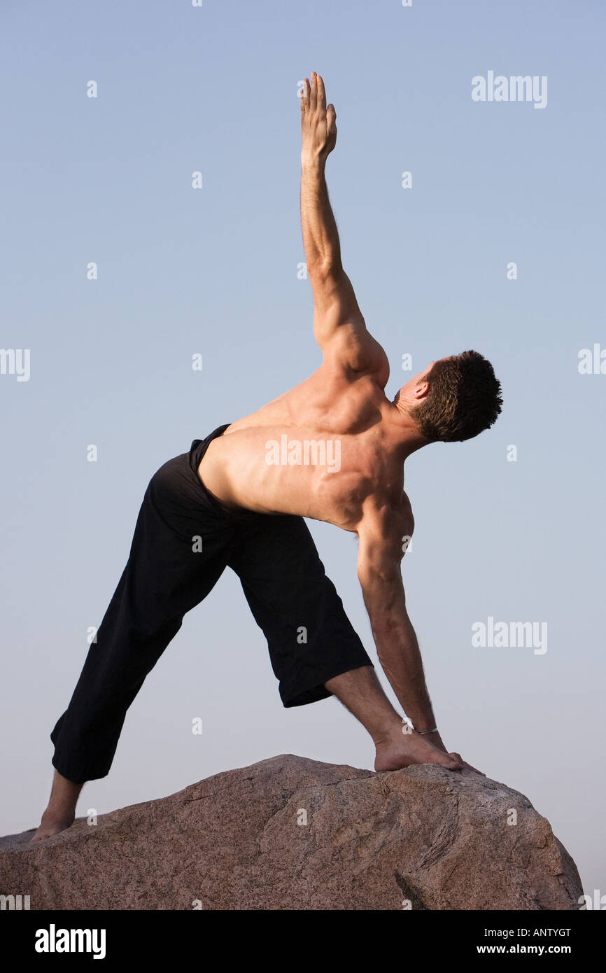 Man performing Hatha Yoga parivrtta trikonasana revolving triangle on a ...