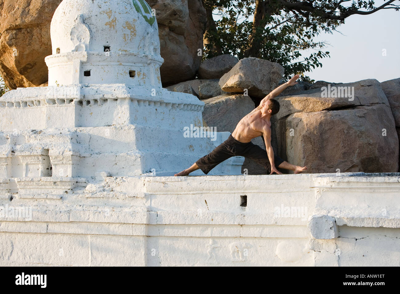 Man performing Hatha Yoga side stretch on a hindu temple in India Stock