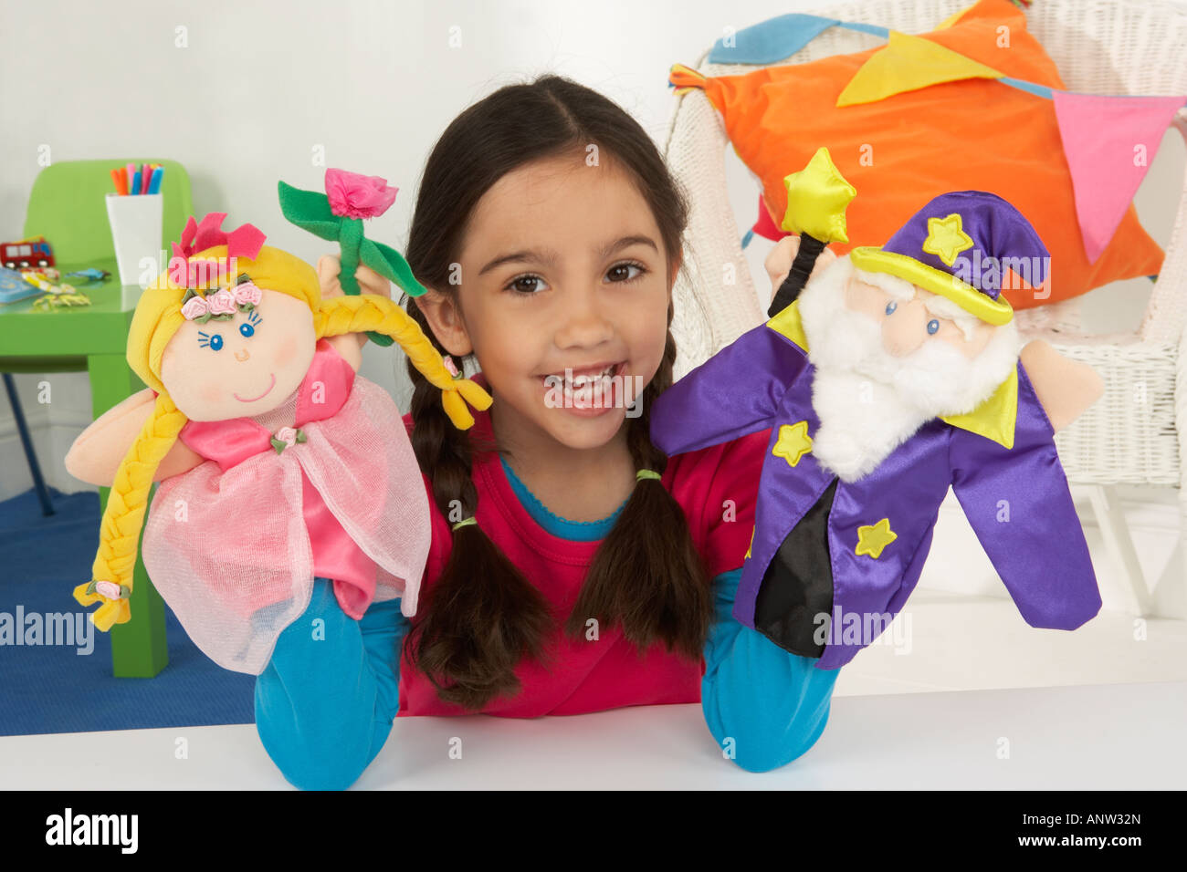 a girl smiles as she plays with a princess and a wizard hand puppet Stock Photo