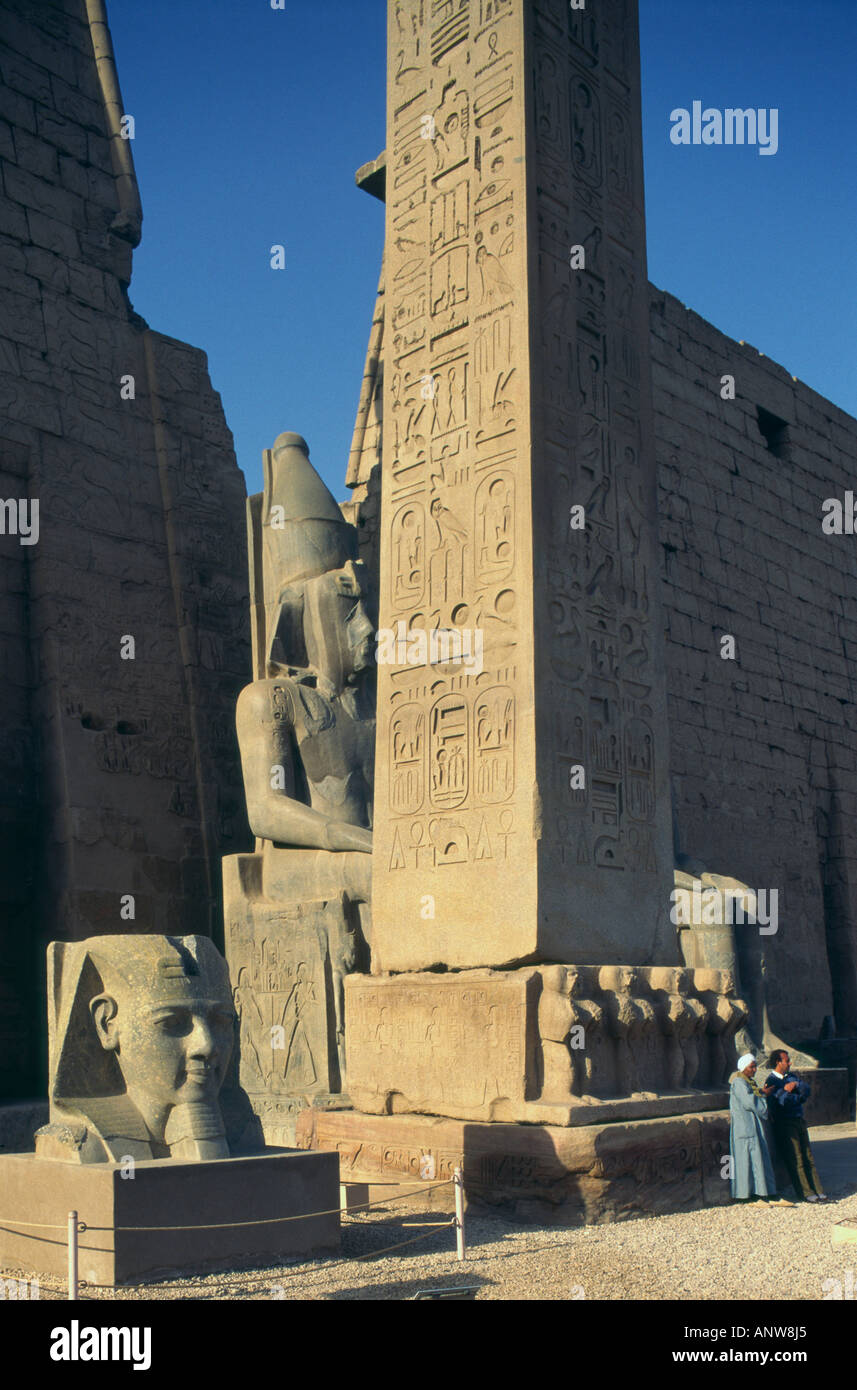 Upper Egypt Luxor East Bank Luxor Temple view with bust of Ramses II obelisk and two local men resting at obelisk basis Stock Photo