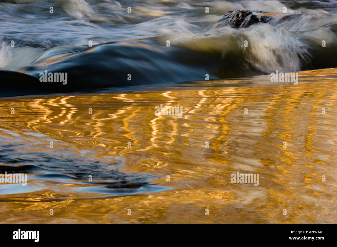 Distorted tree reflections in open water of Junction Creek flowing over dam, Greater Sudbury Ontario Stock Photo